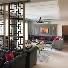 A wider view of the living area, showing how the geometric room divider separates the formal seating area from the rest of the space. This approach allows for an open feel while creating functional, intimate zones.