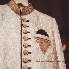 A close-up of the brocade fabric and button details on the groom's wedding outfit.