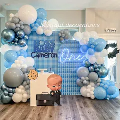 The Boss Baby theme is a huge hit for first birthdays. This setup features a custom gingham and patterned backdrop, a cool 'One' neon sign, and a life-sized character cutout, creating a playful and corporate-cute photo zone.