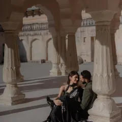 A tender moment shared amidst the majestic pillars of a Rajasthani palace. We seek out these quiet corners within grand locations to capture the personal connection that lies at the heart of your story.