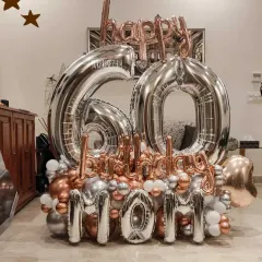 A grand balloon bouquet for a mom's 60th birthday. This arrangement features large silver foil numbers, "Happy Birthday Mom" lettering, and a base of chrome rose gold and silver balloons.