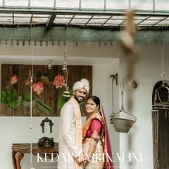A happy portrait of the couple in their traditional wedding attire, captured in a rustic, artistic setting.