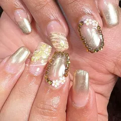 Go for gold with this luxurious set. It combines gold chrome nails, glitter accents, and a statement nail with a border of gold beads and tiny 3D flowers for a truly glamorous look.
