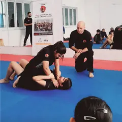 I am personally overseeing a ground defense drill between two female students. Our training is hands-on, with expert guidance to ensure techniques are learned correctly and safely.