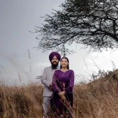 A beautiful portrait of a couple standing in a field of tall, dry grass. The natural setting and their elegant outfits create a lovely contrast, perfect for a rustic pre-wedding shoot.
