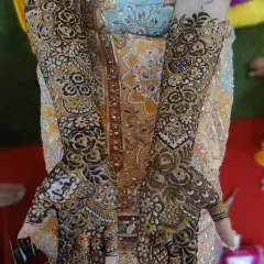 This bride's hands are adorned with a beautiful floral mehndi design that complements her yellow outfit perfectly. The pattern extends from her fingertips to her elbows.