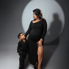 A powerful studio maternity portrait of a mother and her son. The dramatic spotlight on a simple grey background creates a classic and artistic image.