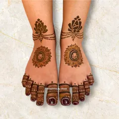 A simple yet stunning feet design. It features a lotus mandala on the foot and a matching lotus anklet design, connected by a delicate chain of dots.