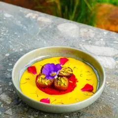 A dessert that's almost too pretty to eat. This vibrant dish is garnished with edible flowers and pistachios, a treat for the eyes and the palate.
