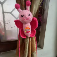 A sweet pink butterfly curtain tie, perfect for adding a whimsical touch to a child's bedroom or nursery. The details in the wings and body are all carefully crocheted.