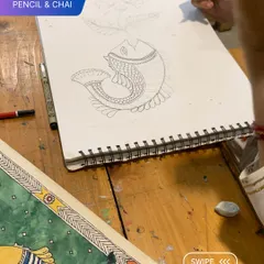 A student practices drawing a fish in the traditional Madhubani style, learning the distinct patterns and line work of this beautiful art form.