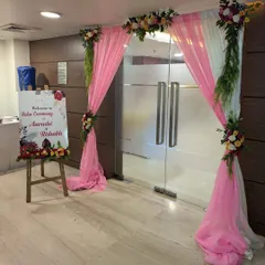A welcoming entrance for a Roka ceremony, featuring draped curtains, floral accents, and a personalized welcome sign on an easel.