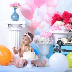 For a classic look, my studio cake smash sessions offer a controlled environment with elaborate backdrops. This setup features pastel balloons and floral arrangements for a soft, celebratory feel.