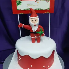 Santa Claus is coming to town! This Christmas cake features a fondant Santa topper on a bed of fluffy "snow" buttercream. It's a festive and fun addition to any holiday gathering.