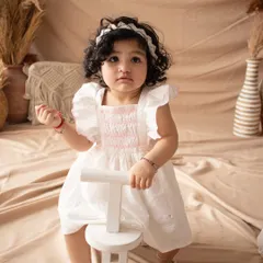 A clean and simple portrait of a birthday girl on a white tricycle against a neutral backdrop.