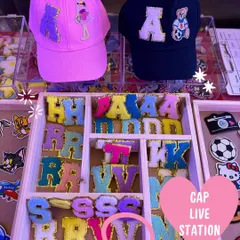 A glimpse of our live cap customization station, showing a variety of colorful chenille initial patches and character designs ready for guests to choose from. This is where the creative fun begins at your event.