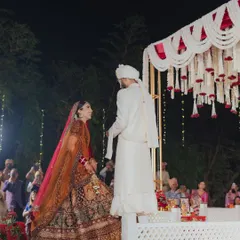 The bride and groom take their first steps towards the mandap. I designed this open-air ceremony with a clean, elevated stage and a stunning floral backdrop of white tuberoses and red roses to create a classic and dramatic effect.