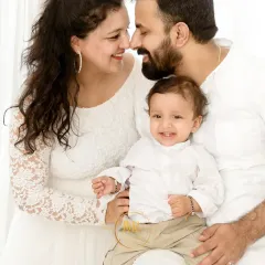 An intimate family moment, with parents smiling and touching noses while holding their baby boy.