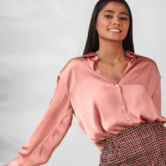 A smiling model wearing layered necklaces, showing how the jewellery looks as part of a complete, styled outfit.