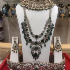 A complete Victorian bridal set with rich emerald green stones, including a choker, layered haram, and a matching vaddanam.