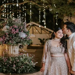 A kiss of love and appreciation. This tender moment between the couple, captured by the flower-adorned fountain, is a beautiful testament to their connection and the romantic atmosphere of their cocktail party.