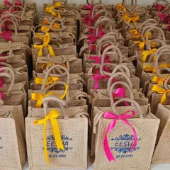 A large batch of personalized jute bags for the 'Eesha' wedding, ready to be filled with goodies for guests. A practical and stylish wedding favor.