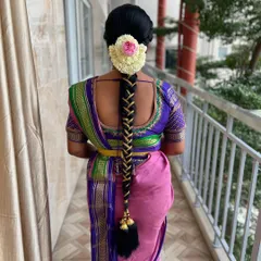 A classic South Indian bridal braid, featuring a long, thick plait adorned with fresh flowers and traditional hair jewelry.