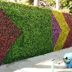 This outdoor artificial green wall features a colorful chevron pattern, creating a vibrant and eye-catching display.