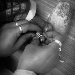 A close-up, black and white shot of the 'Jodi Mettu' or toe ring ritual. This intimate frame highlights a beautiful tradition shared between cultures, symbolizing the start of married life.