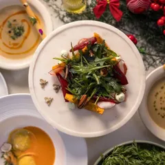 A beautiful top-down view of our Holiday Feast spread, featuring a winter salad with arugula and beetroot, ravioli, and soup.