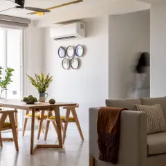 This modern dining space combines natural wood furniture with a light, neutral color scheme for a Scandinavian-inspired aesthetic. The decorative wall plates add a touch of personality and artistry to the minimalist design.