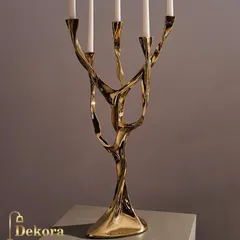 An artistic, tree-like candelabra crafted from polished gold metal. This sculptural piece holds five candles and serves as a dramatic centerpiece for a dining table or boardroom.