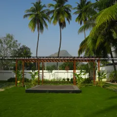 A view of the expansive lawn featuring a modern wooden pergola over a raised deck, set against a backdrop of palm trees and distant mountains.