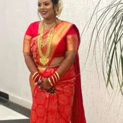 The bride in her magnificent red muhurtham saree. The pre-pleating ensures the drape is immaculate, allowing the rich fabric and her jewelry to shine.