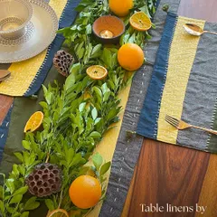 This overhead view showcases a complete table setting using my nature-inspired runner and placemats. The earthy greens, blues, and yellows are complemented by fresh foliage and citrus, showing how these linens serve as a perfect canvas for your own creative table styling.