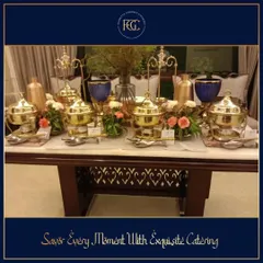 A sophisticated buffet setup on a marble-top table. The arrangement of polished brass chafing dishes and delicate flower bouquets is a perfect example of understated elegance for an intimate gathering.