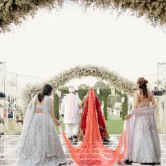 The bride's majestic entrance, her long red veil carried by her bridesmaids, creating a powerful and beautiful image.