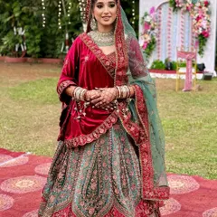 The complete bridal vision. Her radiant makeup, featuring a soft glow and defined eyes, comes together with the magnificent red and green velvet lehenga for a look that is regal, traditional, and absolutely stunning.