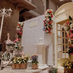 A beautiful decor setup with a European theme, featuring a white bicycle, abundant flowers, and a classic telephone booth.