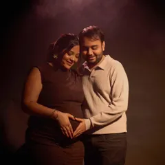 A soft spotlight creates an intimate atmosphere for this couple's portrait. Their hands forming a heart on the baby bump is a classic, tender gesture that I love to capture in a gentle, cinematic style.