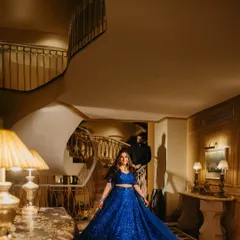 A grand, sweeping shot of Raakhee on the staircase in her dazzling blue lehenga, with Akshay in the background. A true fairytale moment.