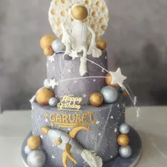 An out-of-this-world cake for a space-themed birthday! This two-tier creation features an astronaut chilling on the moon, surrounded by planets and stars, perfect for a little explorer's big day.