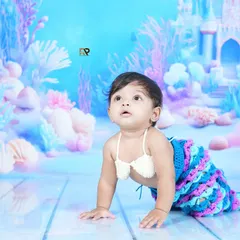 A baby mermaid looks up in wonder at a fish swimming by. This shot captures the magic and curiosity of our underwater-themed sessions.