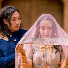 A candid and intimate moment between the bride and groom. The groom lifts the veil, revealing his bride's face, in this beautiful shot that captures a raw and real connection.