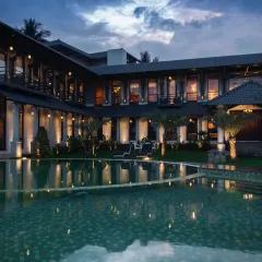 An exquisite interplay of form and reflection, where architectural finesse meets the tranquil embrace of water. This farmhouse, poised with timeless elegance, finds its perfect mirror in the shimmering pool, creating a vision of harmony and refinement at dusk.