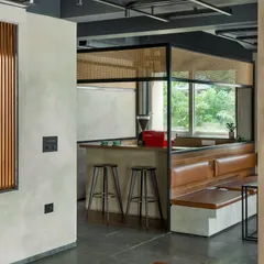 A closer look at the café bar reveals our focus on materiality and clean lines. The design combines wood, concrete textures, and a woven cane screen to create a welcoming yet sophisticated service point that anchors the social hub of the workspace.