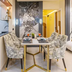 A closer look at the dining setup. The patterned chairs and gold-legged table add a touch of elegance, while the dark marble accent wall provides a bold, modern contrast.