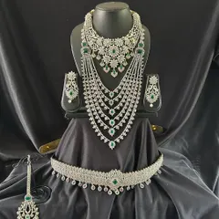 This breathtaking silver-toned bridal set is studded with high-quality white and green stones. The multi-layered necklace and grand choker are designed for a dazzling reception look.
