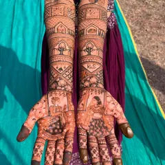 A full bridal design telling the couple's story. On the palms, portraits of the bride and groom are featured, while the arms include initials, banyan trees, and other personal symbols that are significant to them.