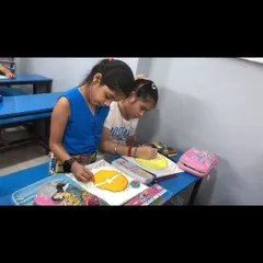 Two students work side-by-side, completely absorbed in coloring their drawings. Our small group sizes ensure that each child receives personal attention and guidance.